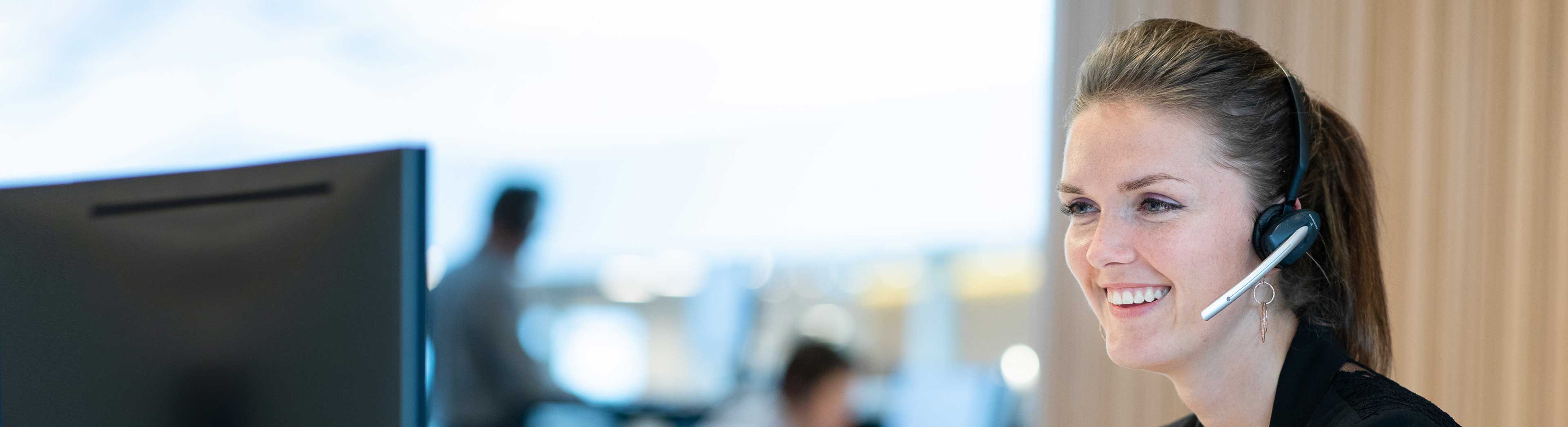 Female customer service representative with a headset looking at a screen